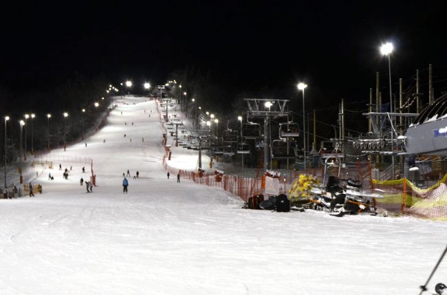 Powiększ zdjęcie: Zdjęcie przedstawia naśnieżony stok narciarski nocą z jeżdżącymi ludźmi. Po prawej stronie wyciąg krzesełkowy.      Źródło: http://www.bbosir.bielsko.pl/cms/upload/wpisy/orginal/23ca3ccd5b.jpg