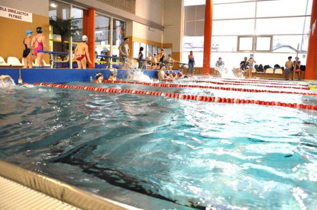 Powiększ zdjęcie: Zdjęcie przedstawia tory pływackie. Dzieci pływające w basenie oraz ludzi dookoła basenu.  Źródło: http://www.bbosir.bielsko.pl/obiekt/kryta-plywalnia-troclik